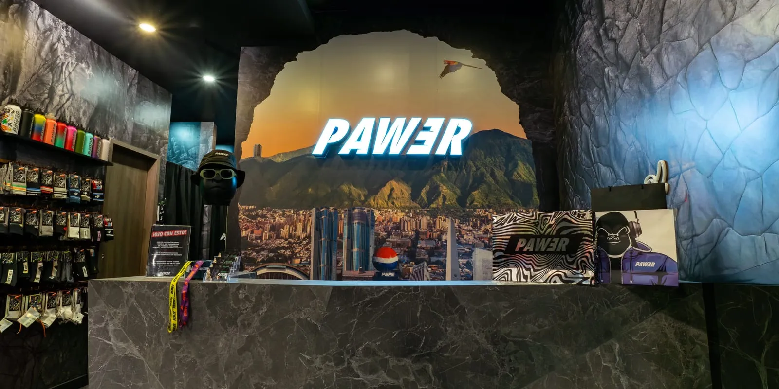 Mostrador de una tienda PAWER ambientada como "Cueva", con el letrero iluminado de la marca sobre un mural de El Ávila